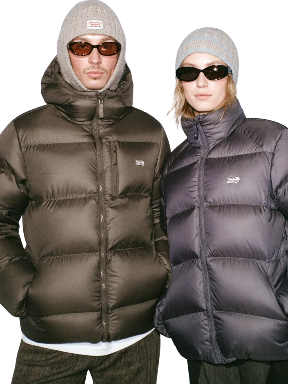 Two models in oversized puffer jackets, beanies and sunglasses
